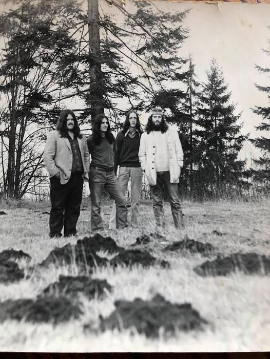 photo showing Washington state rock band Bodhi standing in a field with mole hills in front, trees in back
