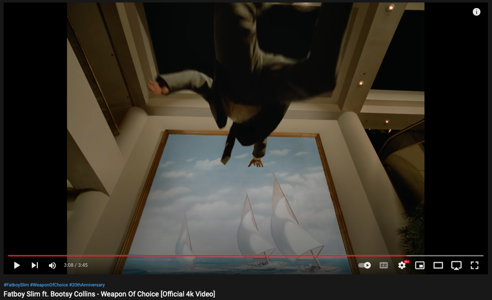 Fatboy Slim - "Weapon of Choice" video still showing man flying towards painting of 3 sailboats on choppy water