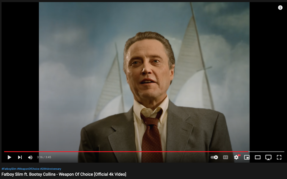 Fatboy Slim - "Weapon of Choice" video still showing man hovering in front of painting with a sail pointing up over each shoulder, winglike
