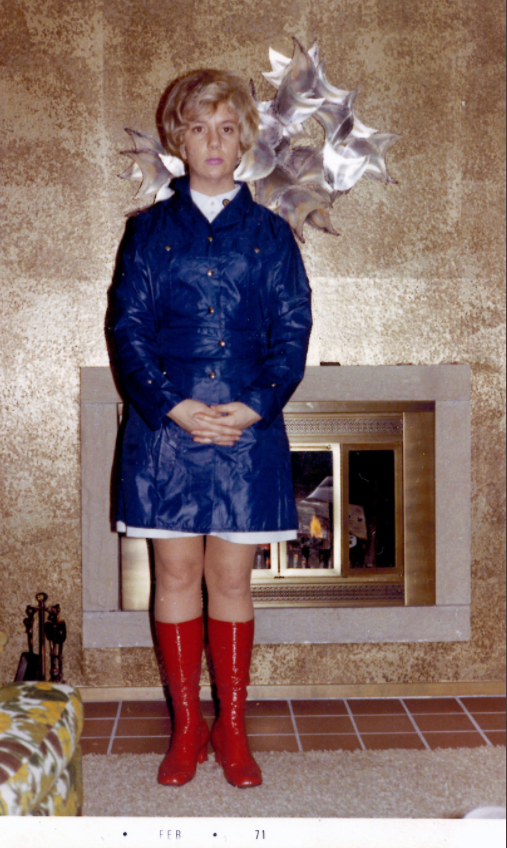 Aunt Marge in in red go go boots and blue raincoat standing before a gold wall and a fireplace